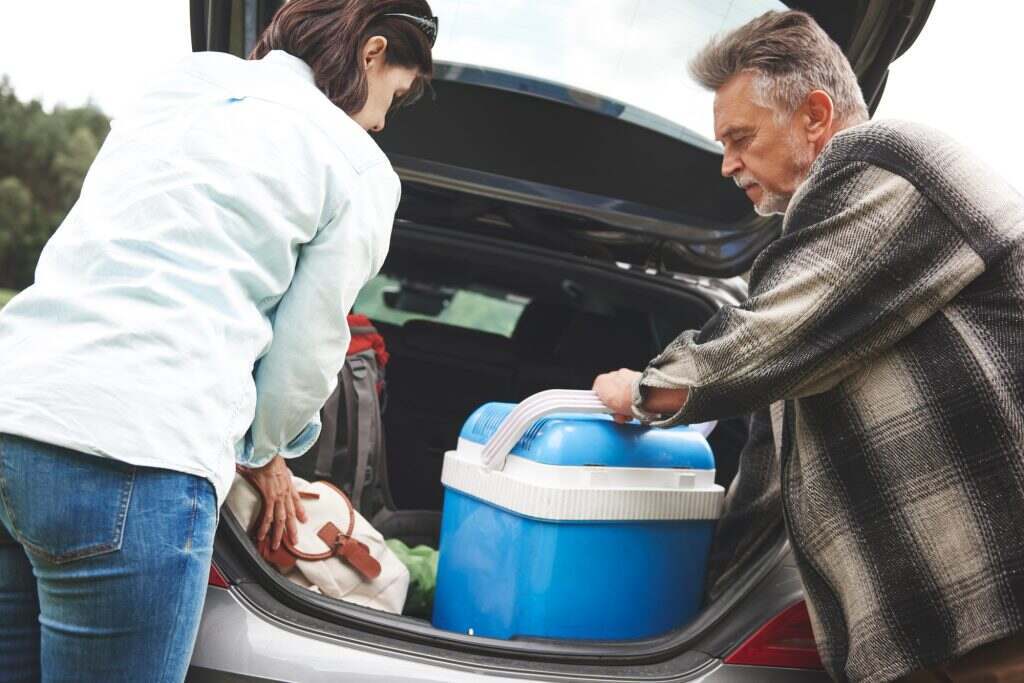 Mature couple removing camping equipment from car boot