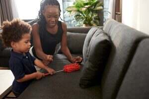 Mother And Son Cleaning Sofa