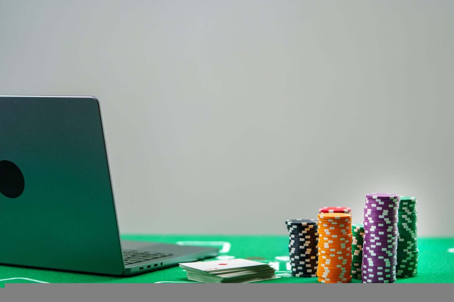 Online poker game setup with colorful chips and playing cards on a green table