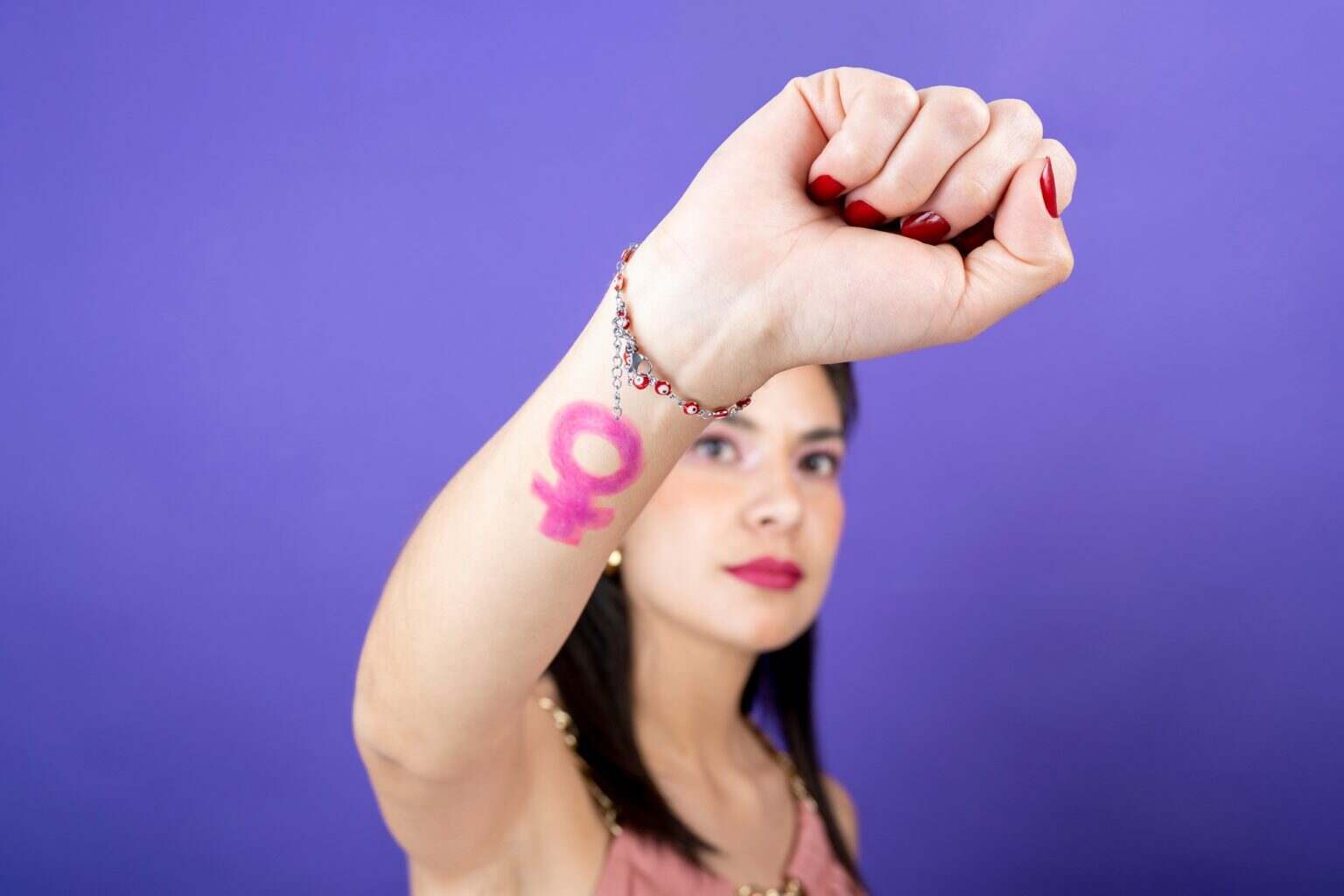 Le violet, couleur emblématique des luttes féministes selective focus of woman raising fist with feminist symbol. rights fight concept
