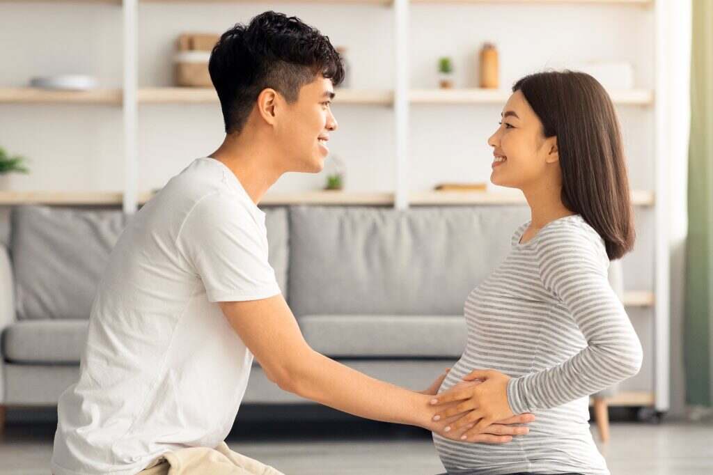 Young asian man helping his pregnant wife exercising