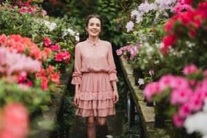 Young beautiful caucasian woman in glass greenhouse among colorful azalea flowers.