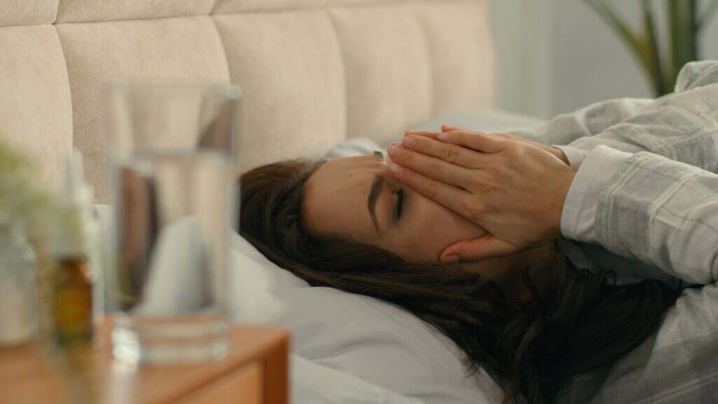 Caucasian European woman lying on bed coughing illness pills treatment at home feeling unwell