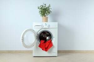 Concept of housework with washing machine against white wall