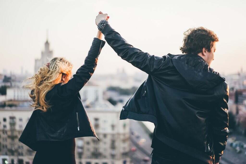 Couple in rock n roll style standing on the rooftop and enjoying sunset,