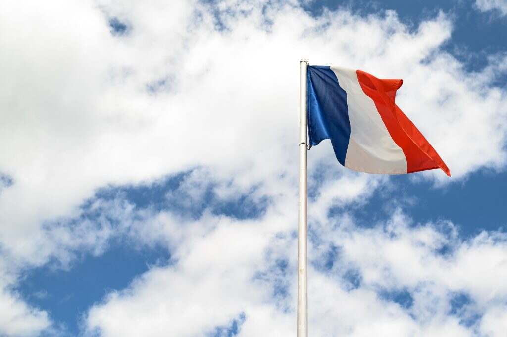 Flag of France against a blue clouded sky