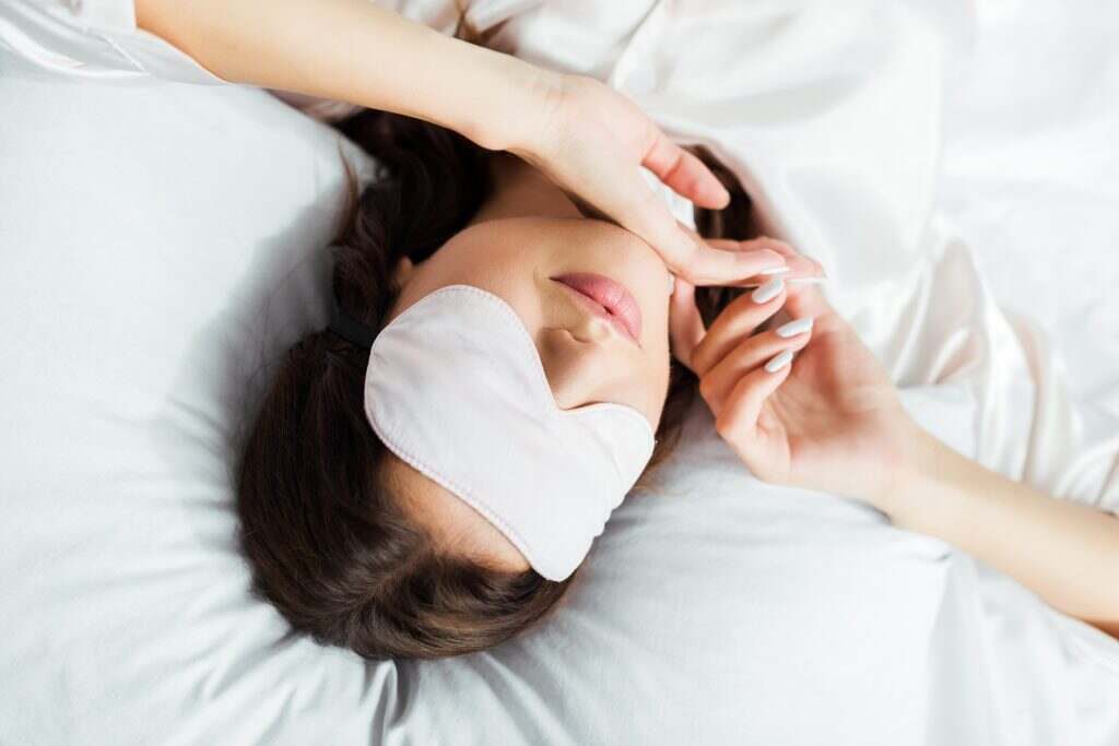 high angle view of woman in sleeping mask lying in bed at morning
