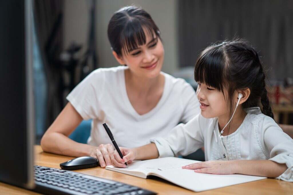 Le système de notation à l’école : comment comprendre la valeur d’une note ? Homeschool Asian little young girl learning online class from school teacher with help from mother