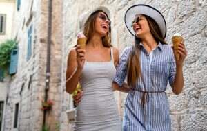 Laughing girls friends eating ice cream cones enjoying their summer vacation