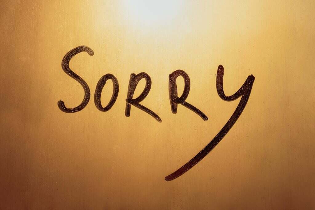 Lettering text Sorry on foggy glass of sunset window