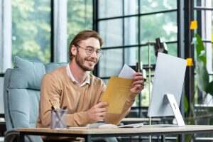 Young successful businessman in casual interior of office, blond man reading postal letter with