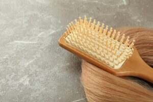 A lock of female hair with hairbrush on gray textured background