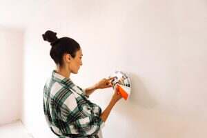 A young woman in casual clothes chooses a color to paint the walls in the house.