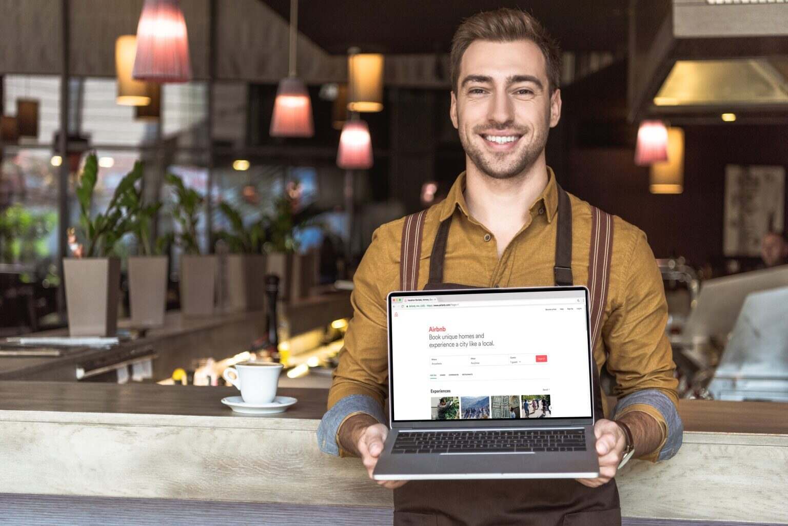 Déclaration d’impôt liée aux revenus Airbnb : les règles à connaître handsome young waiter holding laptop with airbnb website on screen in cafe