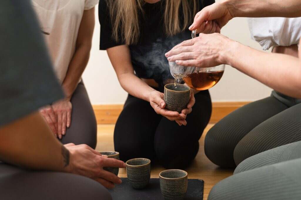 Woman pouring tea to her friends during tea ceremony.
