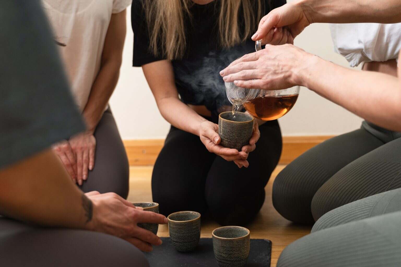 Pourquoi boire du thé le soir : bienfaits, précautions et alternatives Woman pouring tea to her friends during tea ceremony.