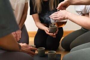 Woman pouring tea to her friends during tea ceremony.