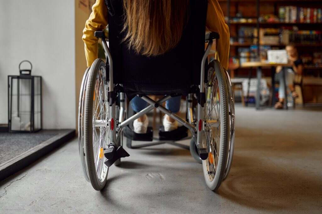 L’accessibilité des logements pour les personnes à mobilité réduite (PMR) Disabled female student in wheelchair, back view