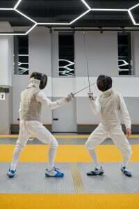 Fencing partners fighting with rapiers practicing attack and defense combination