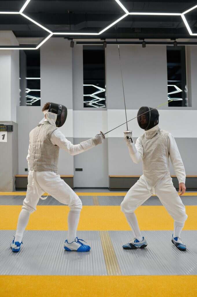 Fencing partners fighting with rapiers practicing attack and defense combination