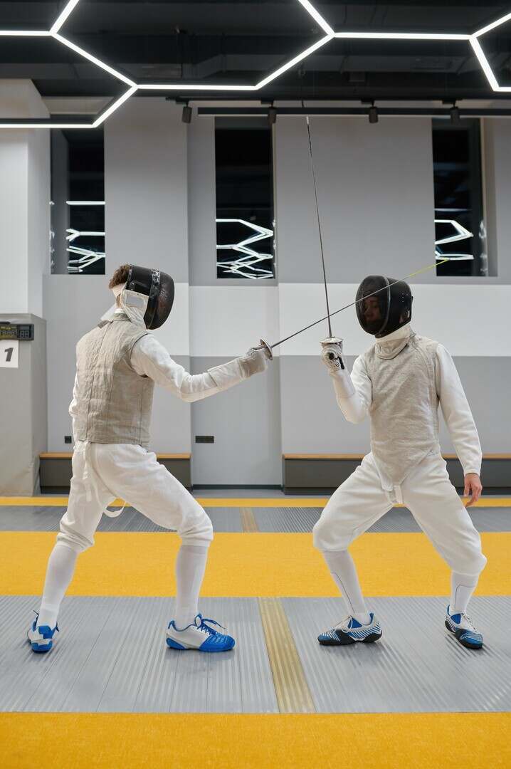 Fencing partners fighting with rapiers practicing attack and defense combination