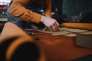 leather craftsman is carefully to make a leather product for a customer. Leather craftsman concept