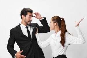 Man and woman anger business hitting on each other screaming with their hands up in the air on a