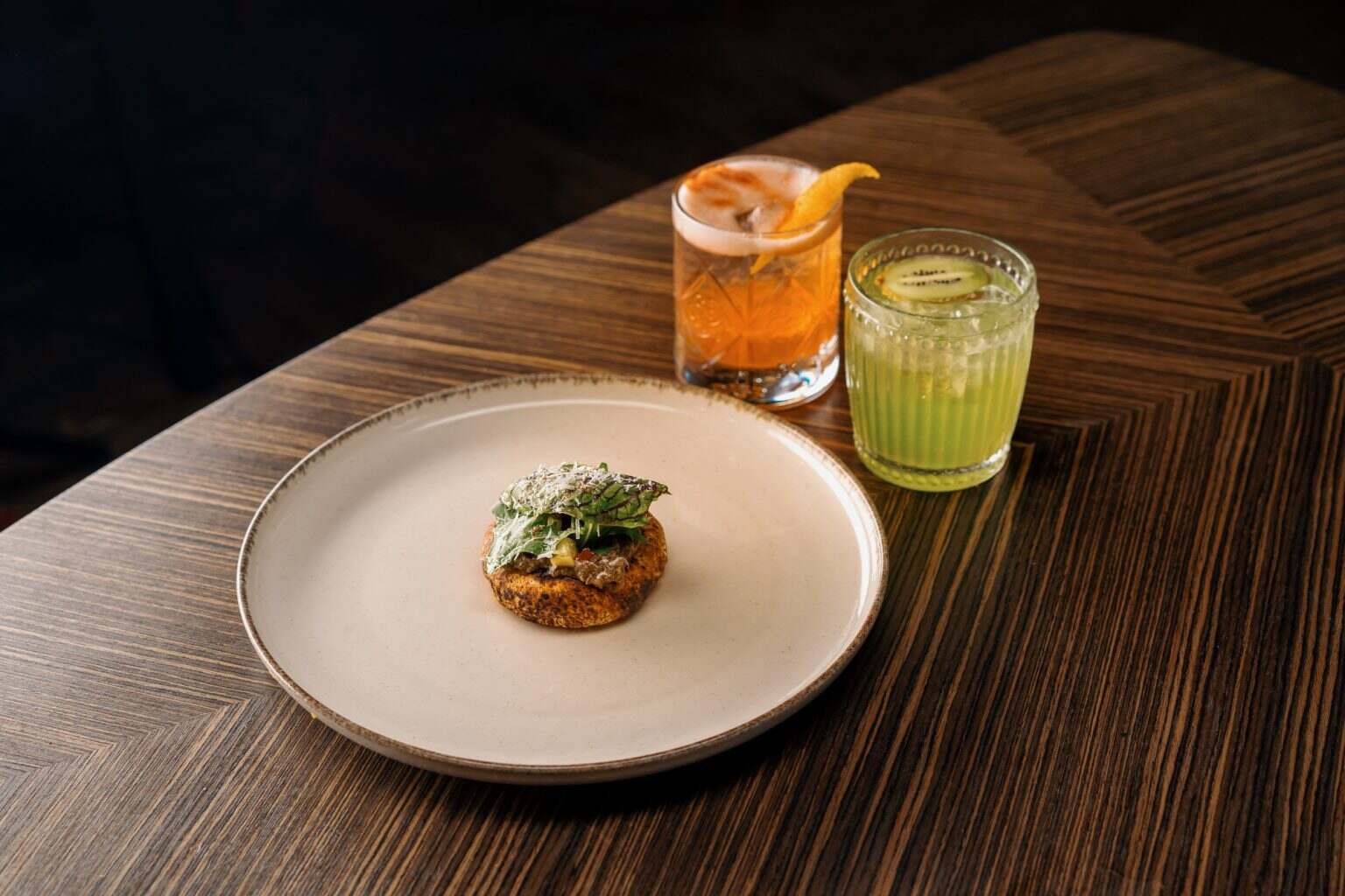 naans with tomato and capsicum sprinkled with cheese are on the table in restaurant with cocktails