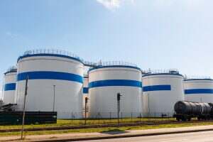 Row many large industrial fuel storage white tanks clear blue sky background on sunny day. Oil