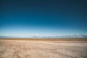 Wide sandy beach with clear blue skies and distant clouds, perfect for nature lovers.