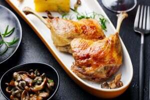 Duck Legs Confit with Potato Gratin and Mushroom Sauce. Close up.