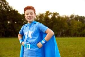 Positive little superhero in park