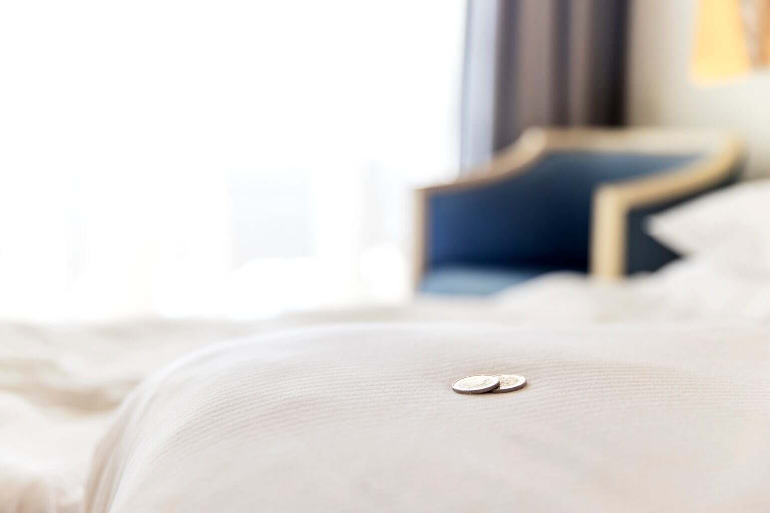 Traditional tips is laying on the corner of bed in hotel room for room cleaner