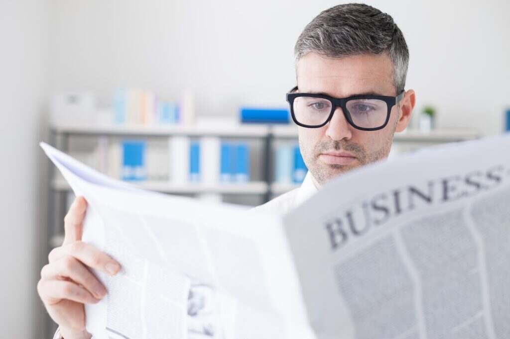 Confident businessman reading a newspaper
