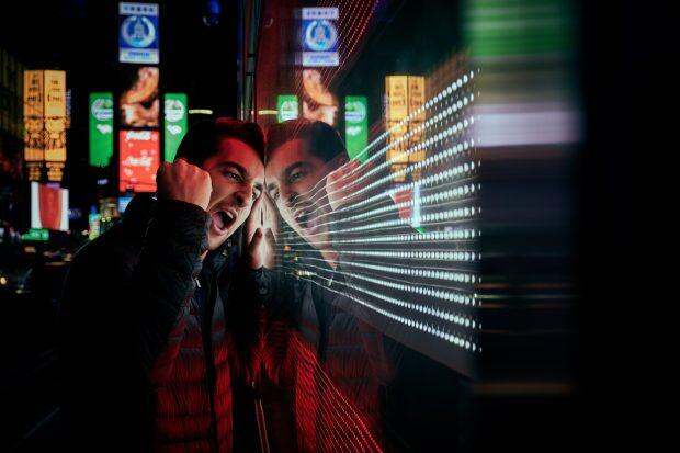 Screaming man hitting glass wall on street