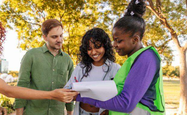 Volunteers reading and signing a petition in a park