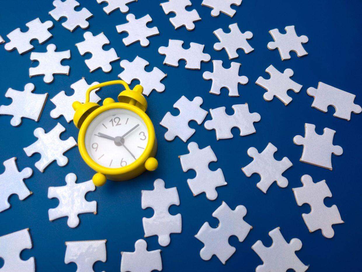 Puzzle 3D : Quand la géométrie devient addiction Yellow alarm clock and white puzzle on a blue background