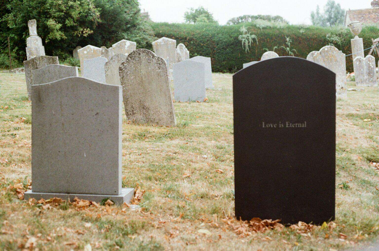 Comment s’habiller pour un enterrement sans commettre d’impair Two gravestones stand in a grassy cemetery