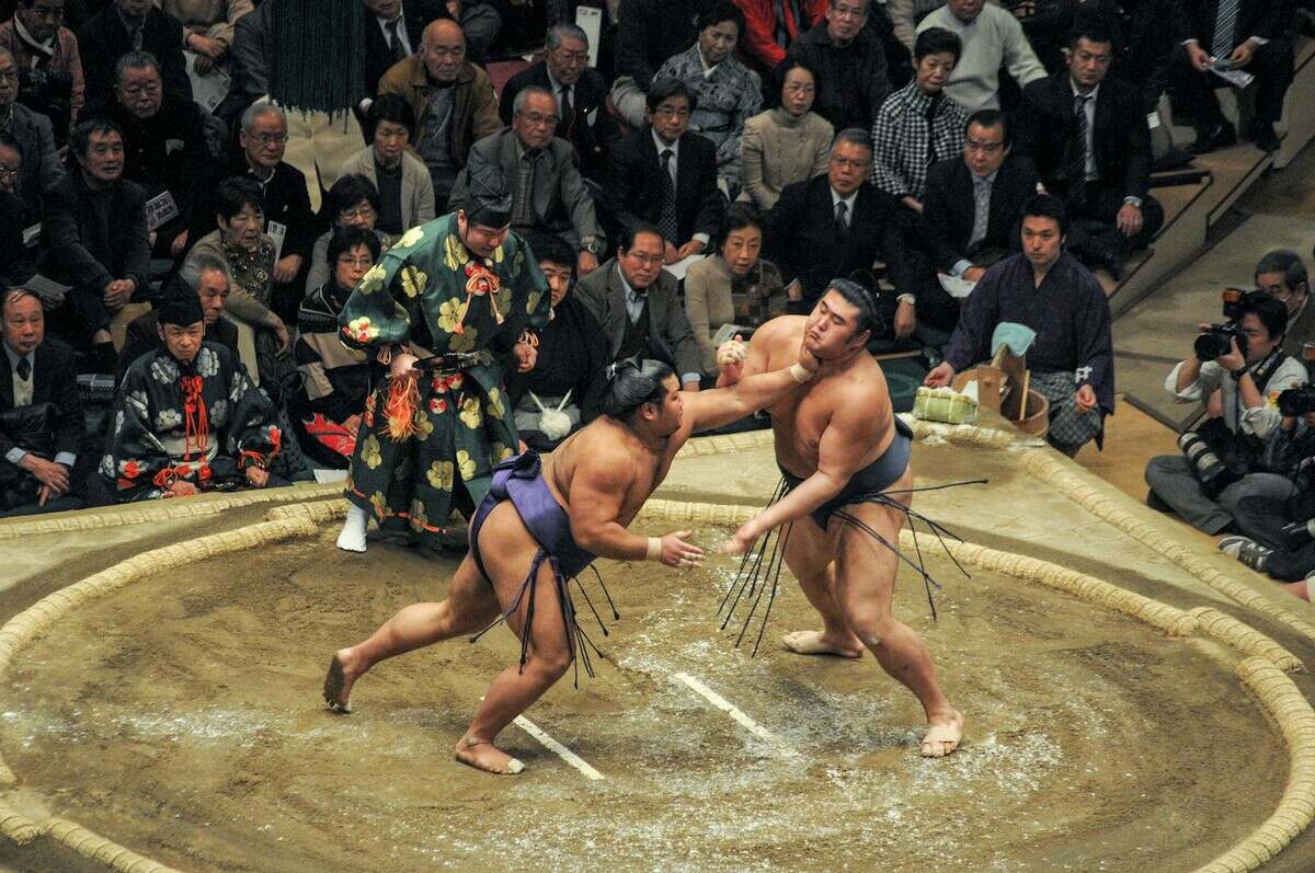 Sumo wrestlers compete in a traditional match with an enthusiastic audience in Japan.