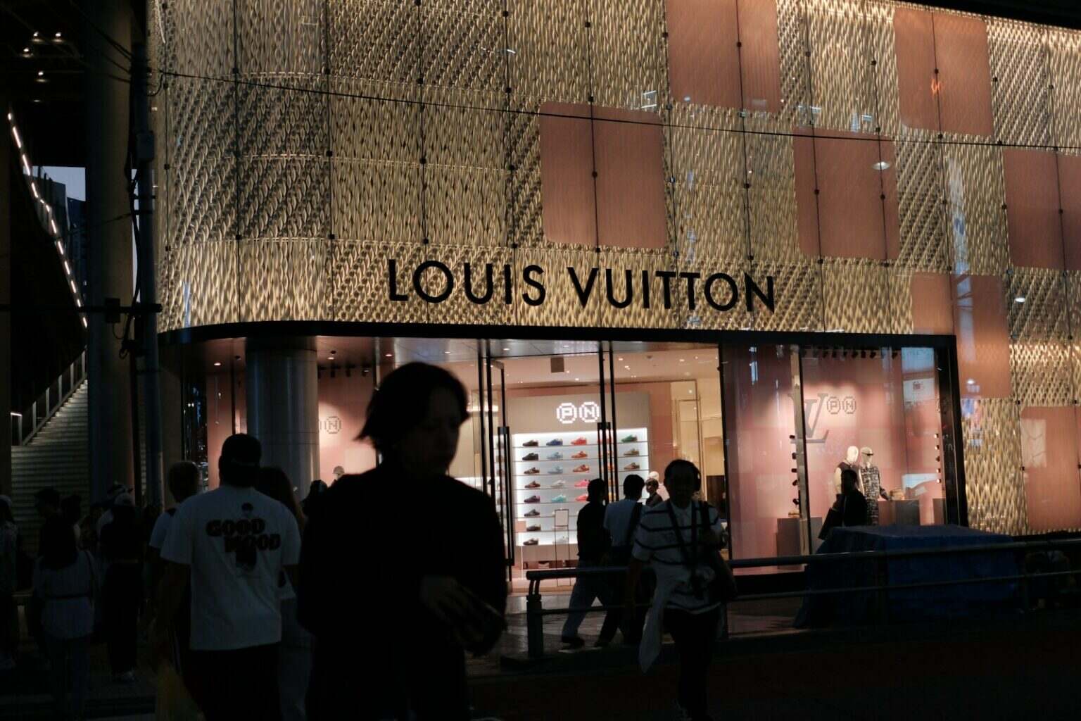 Louis vuitton store exterior at night with people.