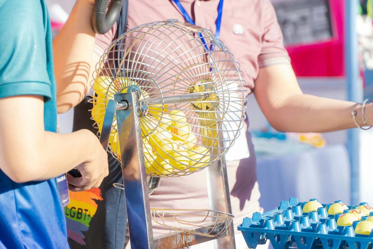 Two people engaging in a bingo game, spinning a cage in a lively, outdoor setting.