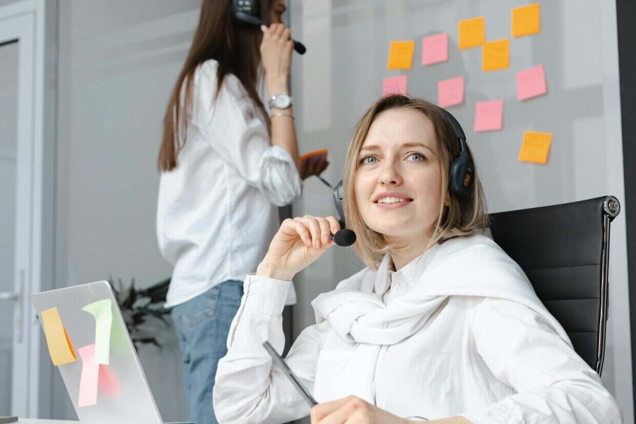 Two women in a professional call center office working and communicating with clients.