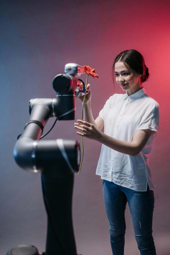 A woman engaging with a robot holding a red flower, showcasing technology and innovation.