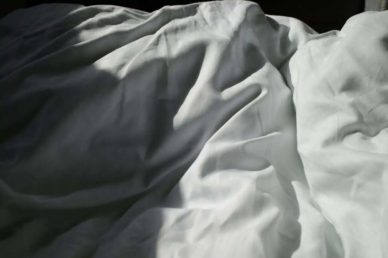 an unmade bed with white sheets and white sheets