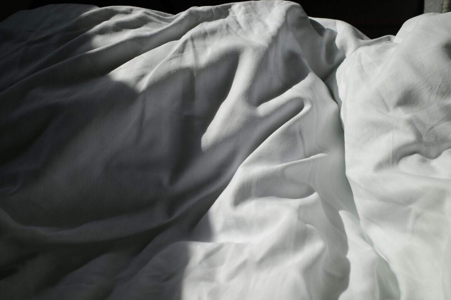 Matelas pour deux : comment éviter les nuits conflictuelles an unmade bed with white sheets and white sheets