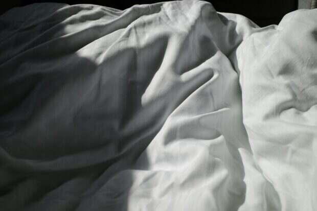 an unmade bed with white sheets and white sheets