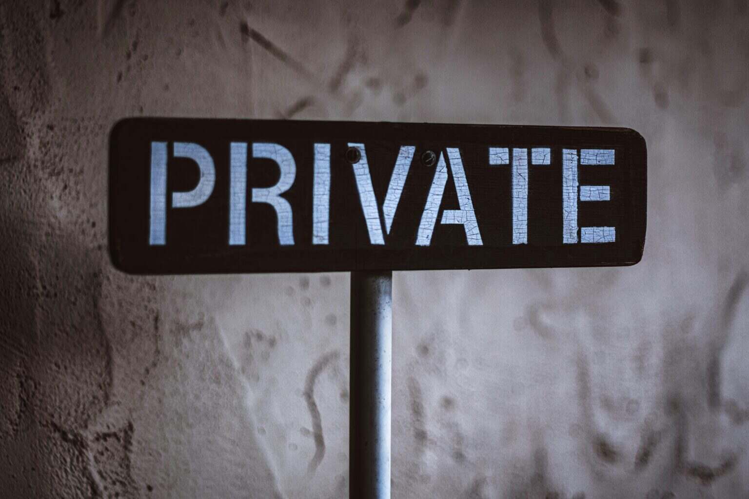 A weathered 'Private' sign on a rustic wall background in Solvang, California.