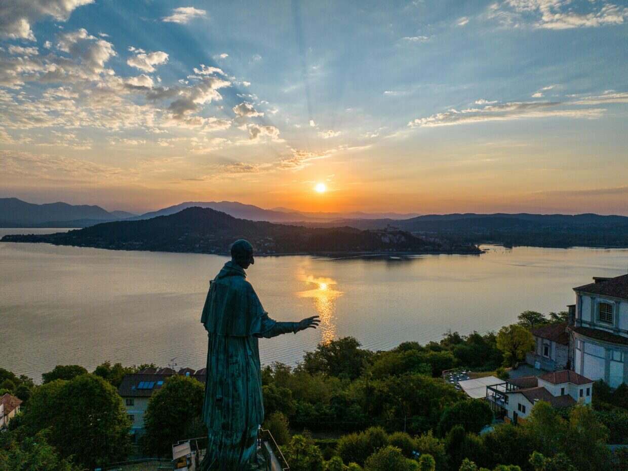 Dramatic sunset scene with a statue overlooking Lake Maggiore in Italy.