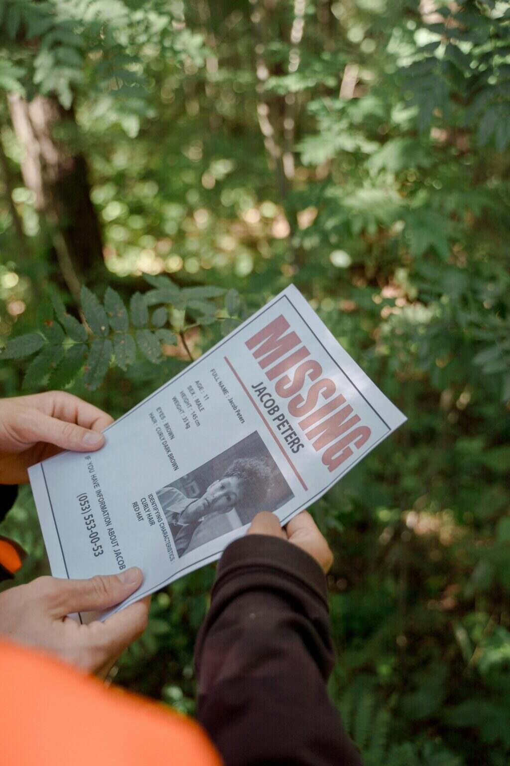Pourquoi les Démogorgons ont disparu dans le final de Stranger Things, expliqué par les créateurs de la série Two hands holding a missing person flyer in a forest setting, implying search or investigation.