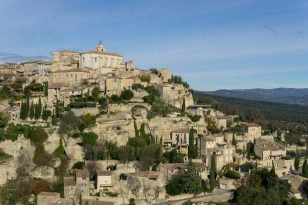 Hilltop village with ancient stone buildings and cypress trees.